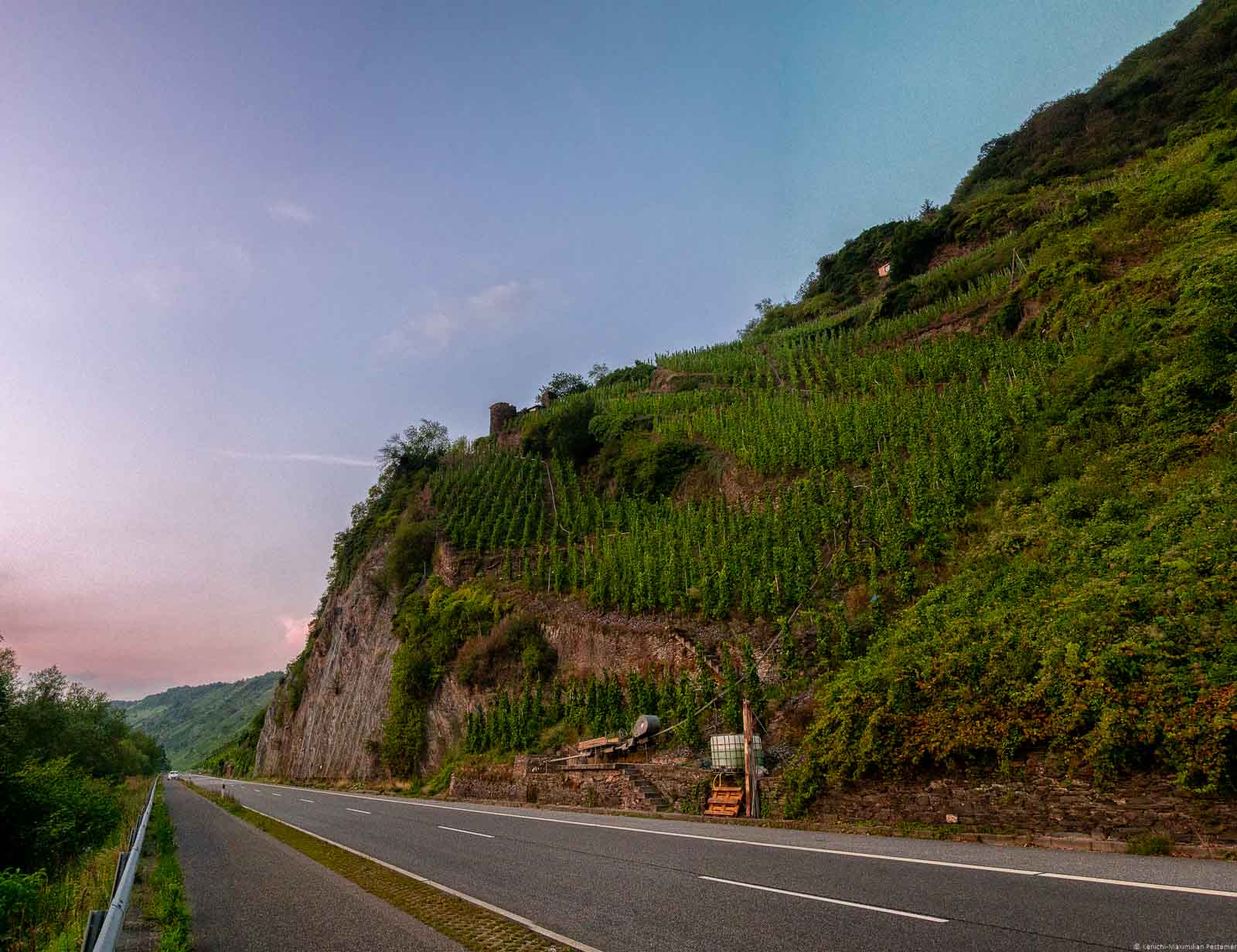 Der Weinberg Trabener Zollturm liegt an der Mosel. Dieses Foto stammt von einem Sonnenuntergang. Der Turm befindet sich auf einem Felsen über einer Straße.