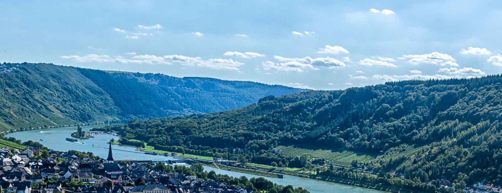 Ort im Vordergrund, Fluss, Weinberge u.a. Trabener Königsberg, Wälder, Hänge und bewölkter Himmel