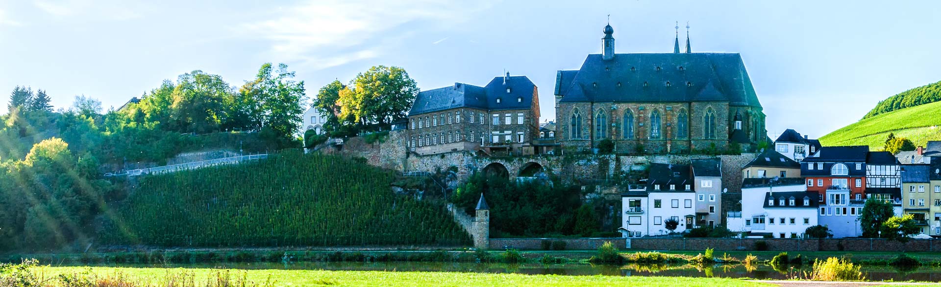 Auf dem Berg liegt die Laurentiuskirche. Unterhalb der Kirche liegt der Weinberg Saarburger Laurentiusberg und der Fluss Saar.