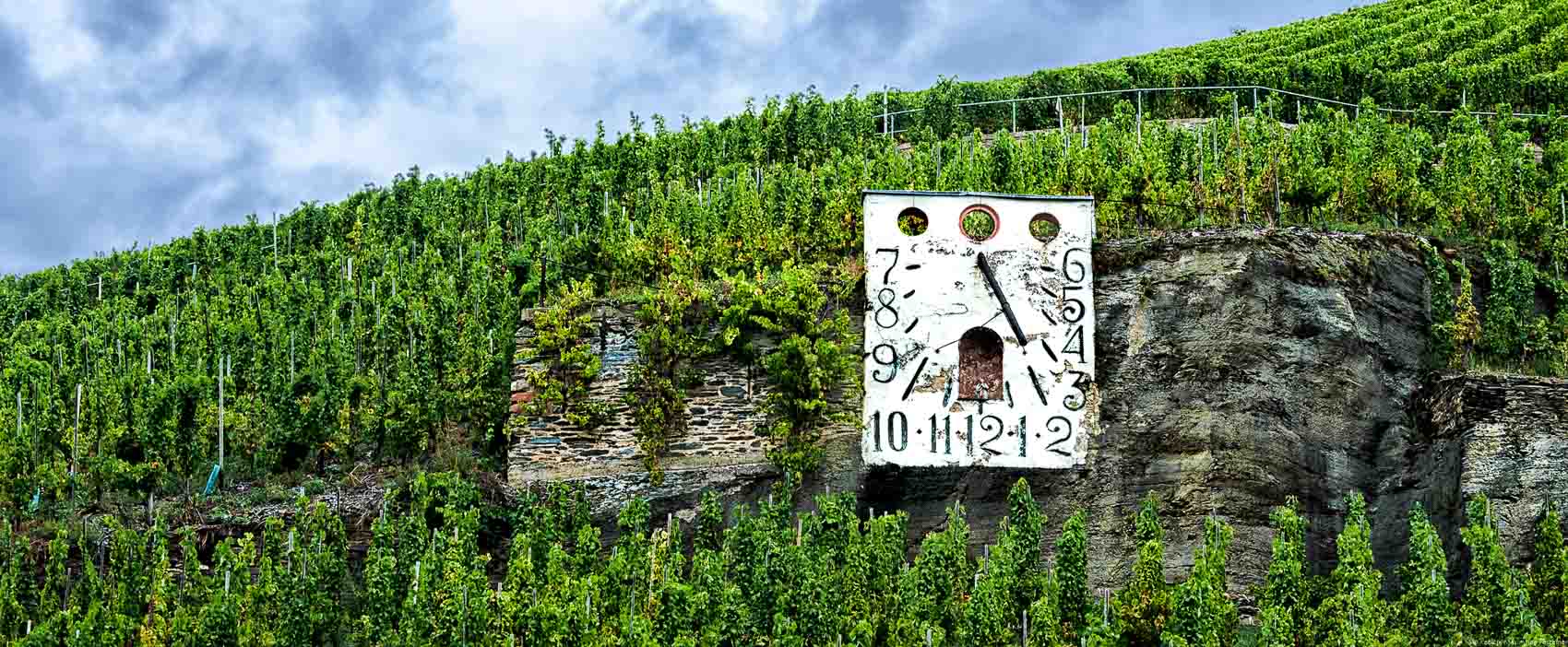 Zeltinger Sonnenuhr im Fels an Weinberg mit Wolken im Hintergrund
