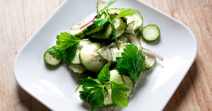 Gurkensalat mit Zwiebeln auf kleinem weißen Teller