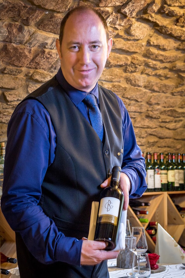 In Schnabel Restaurant präsentiert Jürgen Schnabel einen Rotwein. Im Hintergrund erkennt man den stilvollen Gewölbekeller.