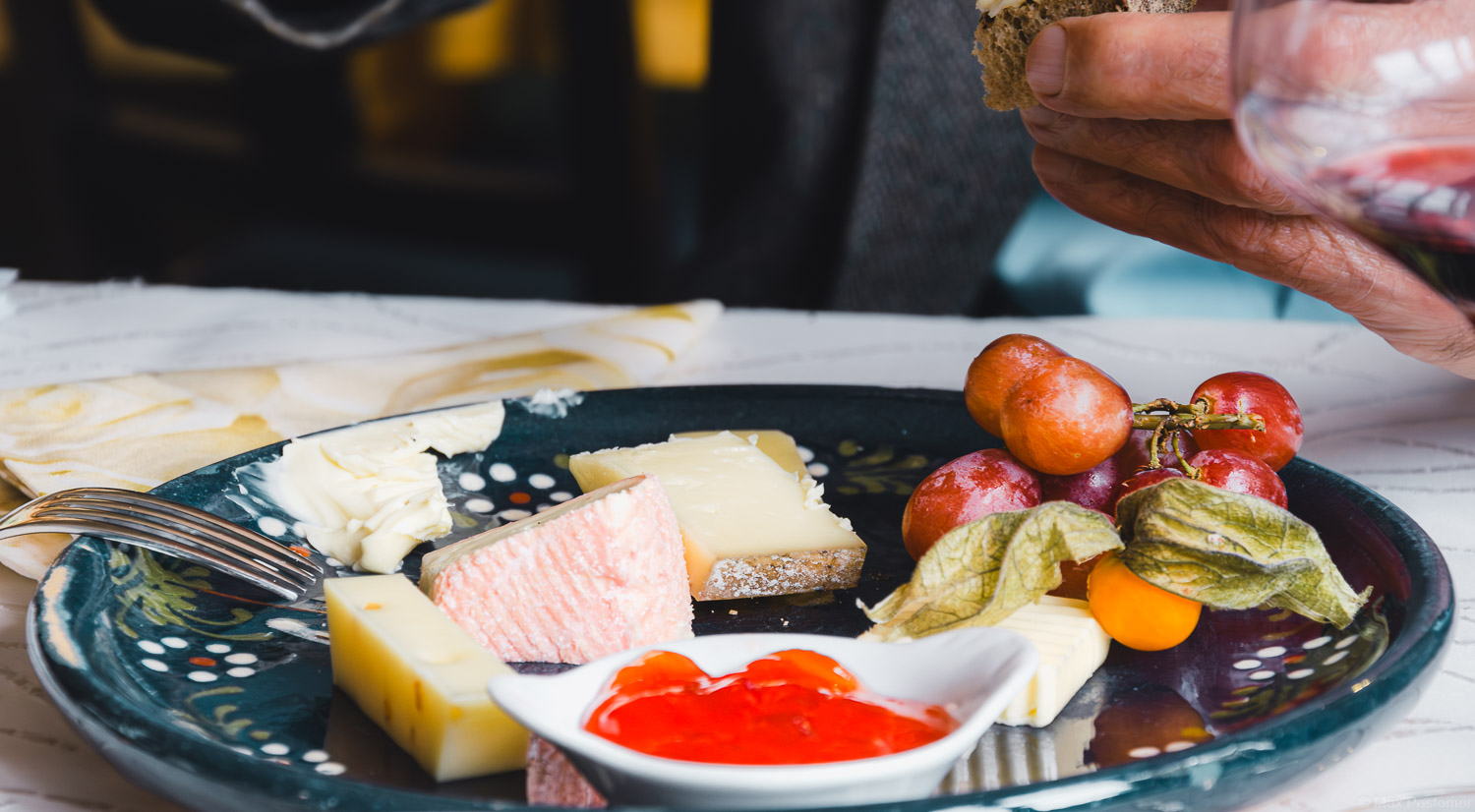 Käseteller mit Brot und Trauben zum Wein auf blauem verzierten Teller.